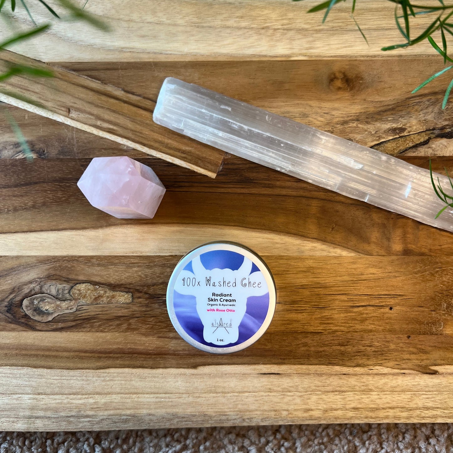 Top view of jar of 100x Washed Ghee Ayurvedic Skin Cream with Rose Otto essential oil on a wooden board with a rose quartz crystal and selenite crystal.