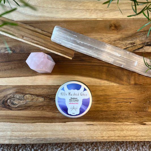 Top view of jar of 100x Washed Ghee Ayurvedic Skin Cream with Rose Otto essential oil on a wooden board with a rose quartz crystal and selenite crystal.
