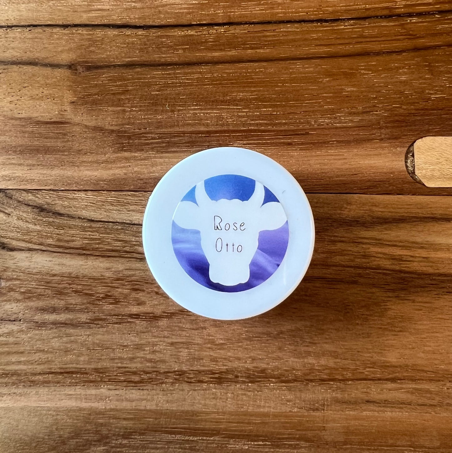 View looking straight down on a 0.25oz jar of 100x Washed Ghee Ayurvedic Skin Cream with Rose Otto (Shata Dhauta Ghrita) on a wooden table.