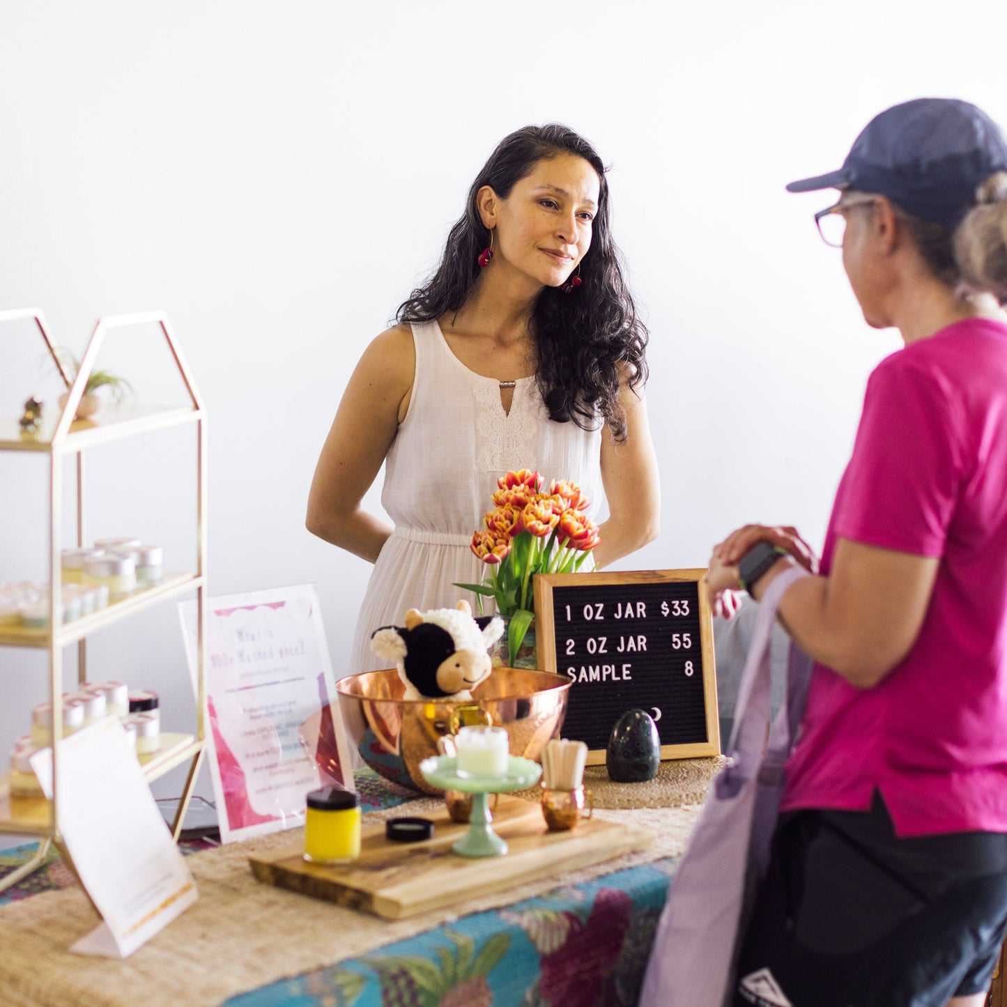 Amarylis Fernandez listens to a customer at her 100x Washed Ghee Ayurvedic Skin Cream sales booth.