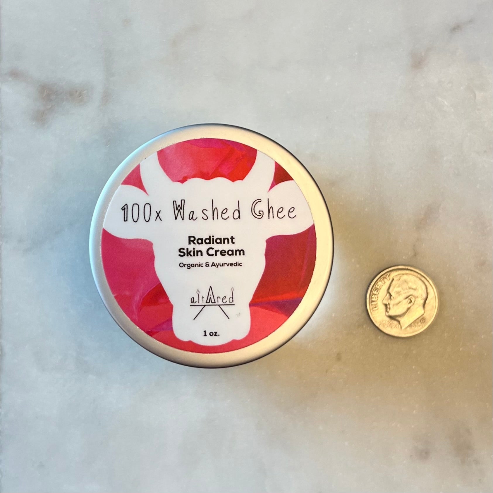 View looking straight down on a glass jar of 100x Washed Ghee Ayurvedic Skin Cream (Shata Dhauta Ghrita) on a wooden table with dime next to it for size comparison.